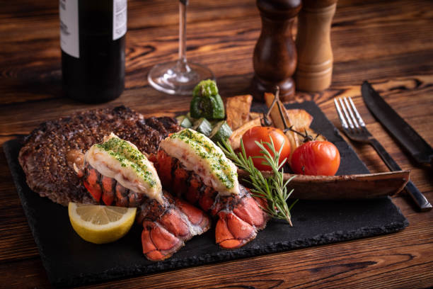 surf and turf with tomahawk rib eye steak and lobster tail surf and turf with tomahawk rib eye steak and lobster tail lobster seafood photos stock pictures, royalty-free photos & images