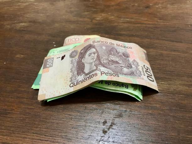 istock Many mixed Mexican peso bills spread over a wooden desk 1156757281