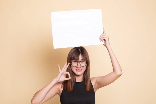 istock Young Asian woman show OK with  white blank sign. 1156762321