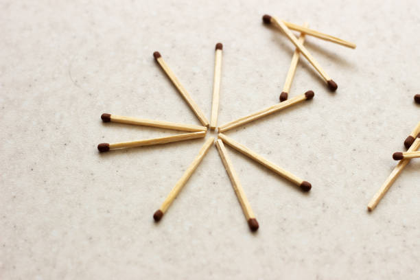 istock Matches scattered around on a table - concept of security. Unused matches on white surface. Matches the shape of the sun. Used matches. Used matches on white surface 1156762388