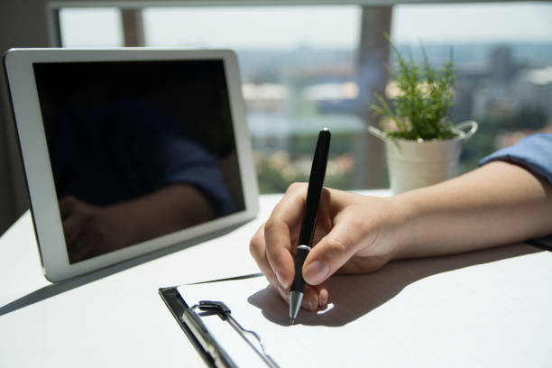 istock Business woman hand is writing on a notepad with a pen. Close up 1156762811