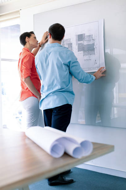 istock Architects discussing over blueprint on glass board in a modern office 1156765004