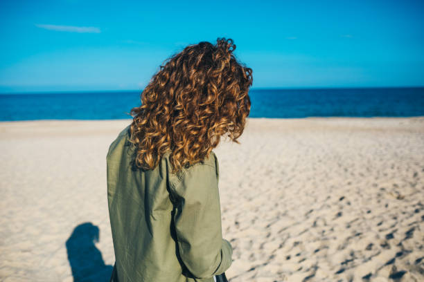 istock Back view unrecognizable young curly-haired woman 1156772614
