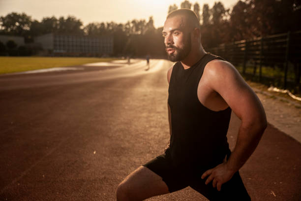 istock One young man, athlete stretching, upper body shot. Outdoors, on a hot Summer day. 1156773297
