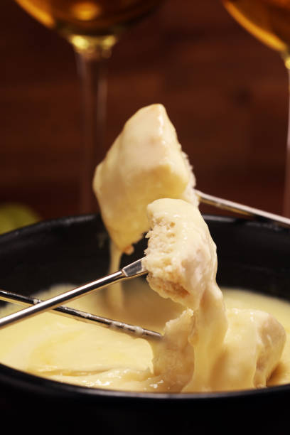 istock Gourmet Swiss fondue dinner on a winter evening with assorted cheeses on a board alongside a heated pot of cheese fondue 1156776365