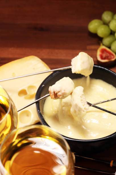 istock Gourmet Swiss fondue dinner on a winter evening with assorted cheeses on a board alongside a heated pot of cheese fondue 1156777258