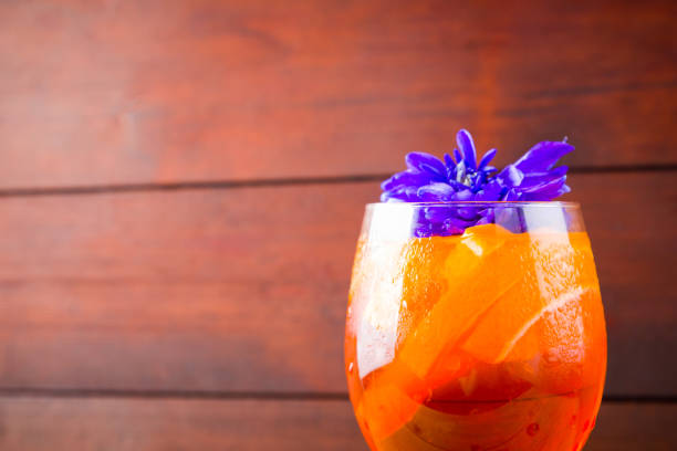Spritz cocktail on wooden boards. Summer alcoholic cocktail with orange slices and flowers. Spritz on wooden boards