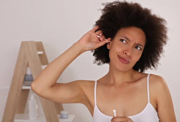 istock Cleaning ears. Woman using a cotton bud to clean her ear. 1156785040