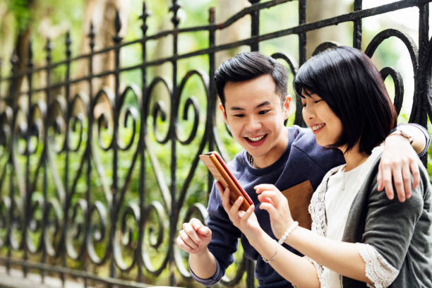 istock Couple using smartphone in public park 1156786427