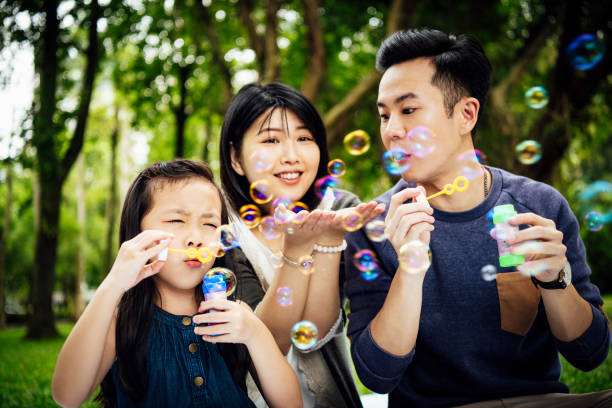 istock Family using bubble wands in park 1156786940