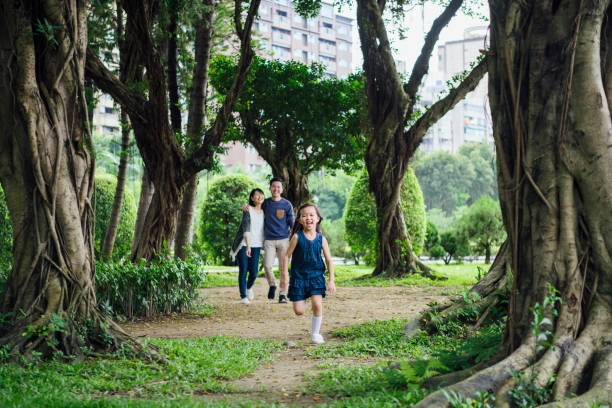 istock Girl running on path in park with parents behind 1156786962