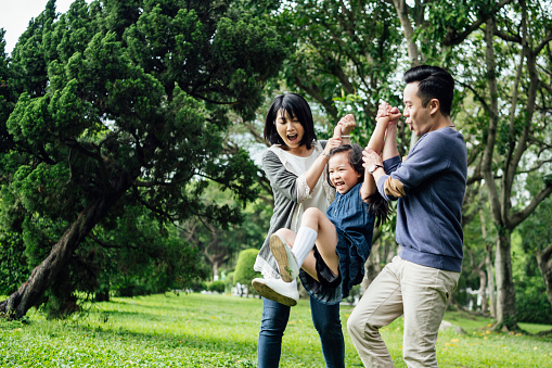 Action shot of happy Chinese girl playing with mother and father, bonding, togetherness, trust