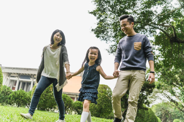 istock Family smiling and holding hands on walk in park 1156786973