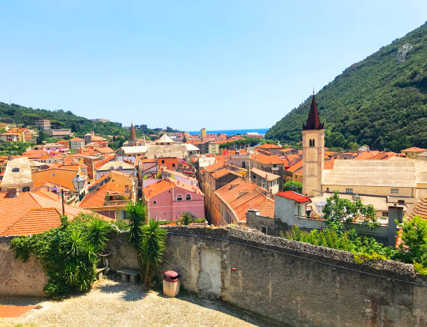 Wonderful italian small town in Liguria region. View on houses with colorful roofs and a church, mountains. Finale ligure nature finale ligure stock pictures, royalty-free photos & images