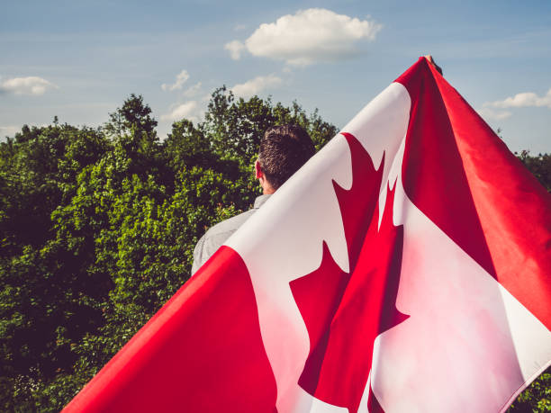 uomo che sventola una bandiera canadese. festa nazionale - travel the americas human age viewpoint foto e immagini stock