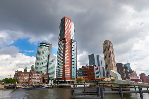 The Skyline of Rotterdam City with the river meuse and several large office buildings captured on a cloudy day during spring season.