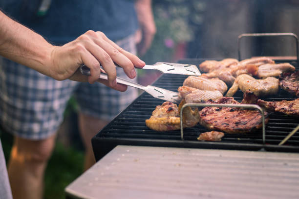 夏のバーベキューでチキンとステーキのマリネを調理する人々。 - flambe ストックフォトと画像