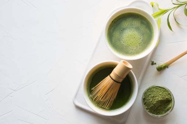 istock Ceremony green matcha tea and bamboo whisk on white concrete table. Top view. 1156795114