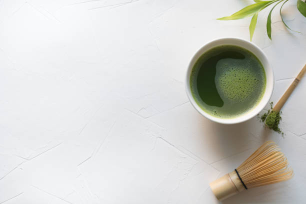 istock Ceremony green matcha tea and bamboo whisk on white concrete table. Top view. 1156795116