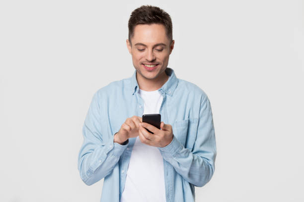 istock Smiling Caucasian man isolated on grey background using smartphone 1156795124