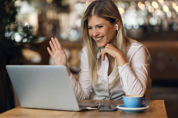 glückliche geschäftsfrau macht einen videoanruf über laptop und winkt jemandem zu - cafe laptop espresso business stock-fotos und bilder