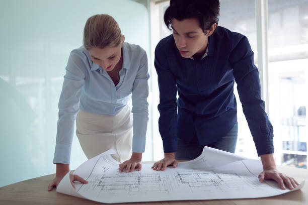 istock Male and female architects discussing over blueprint in office 1156799089