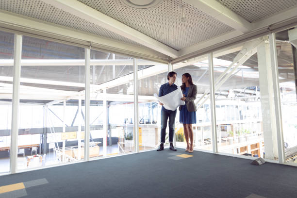 istock Male and female architects discussing over blueprint in office 1156799676