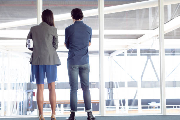 istock Male and female architects looking through window in office 1156799925
