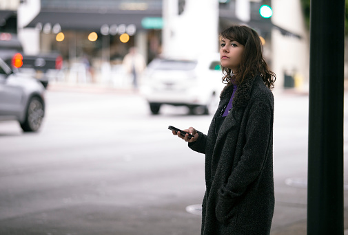 Peatón femenino esperando con el teléfono celular para un paseo compartido photo