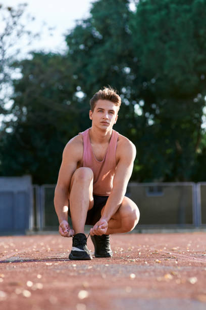 istock Young man runner tying shoelaces on stadium. 1156809589