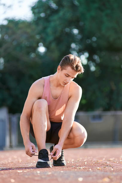 istock Young man runner tying shoelaces on stadium. 1156811577