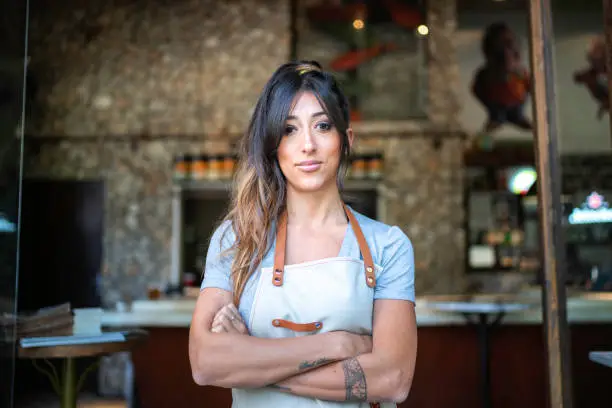 Confident business owner standing at the entrance of a restaurant