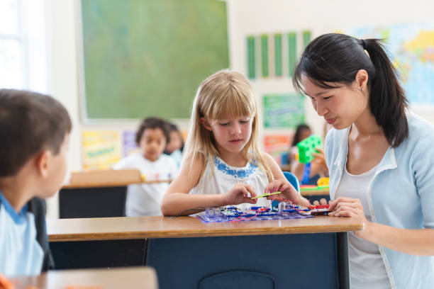 istock Young Asian Teacher Helping Female Caucasian Student 1156823604