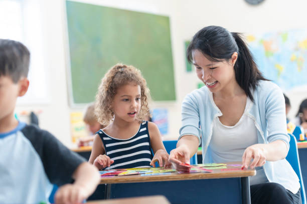 istock Young Asian Teacher Helping Female Caucasian Student 1156823607
