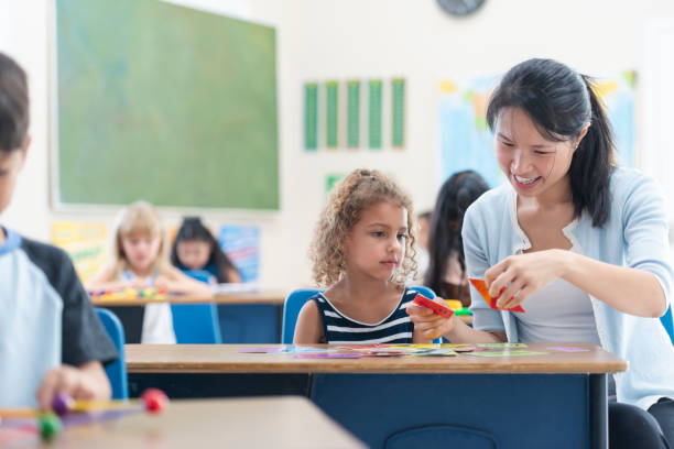 istock Young Asian Teacher Helping Female Caucasian Student 1156823610