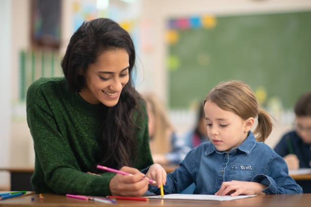 istock Beautiful teacher helps her student finish colouring her page 1156824179