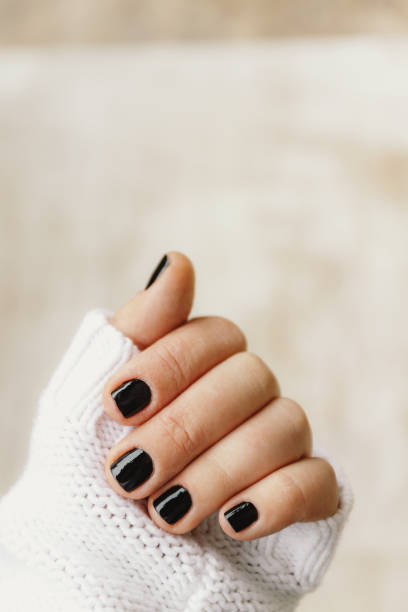 istock hand with black manicure on short nails in a white sweater on a light background. The concept of a stylish and warm winter 1156824224
