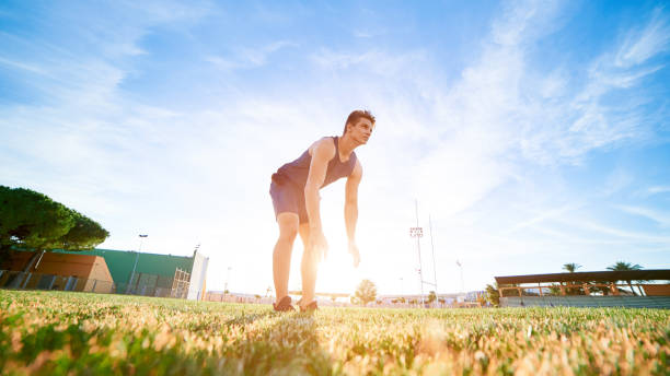 Young muscular man doing exercises on stadium