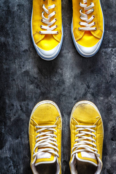 yellow old worn dirty torn sneakers and and new sneakers on a dark grunge background. top view. Copy space. stock photo