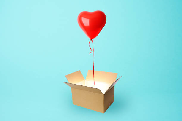 istock Red heart-shaped balloon floating from a cardboard box 1156827251