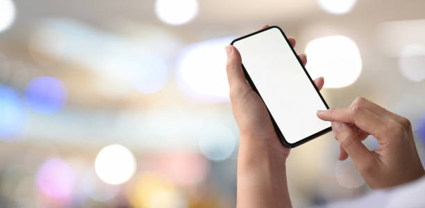 istock Man with mobile phone showing blank screen over bokeh background 1156829800