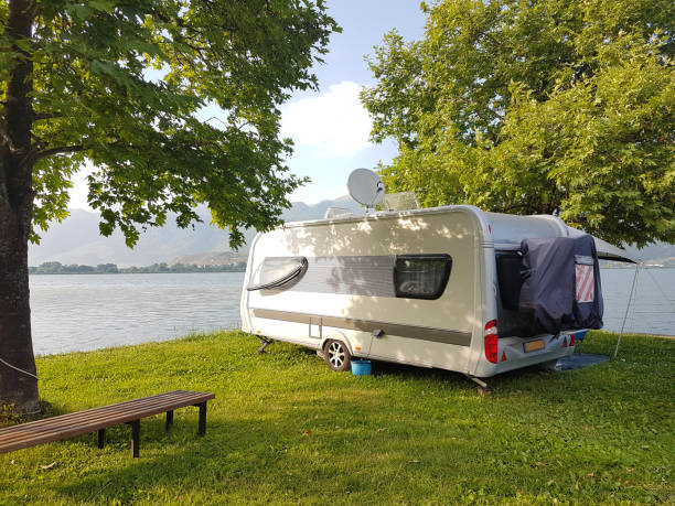 istock caravan car on the camping green grass and tress beside lake 1156830557