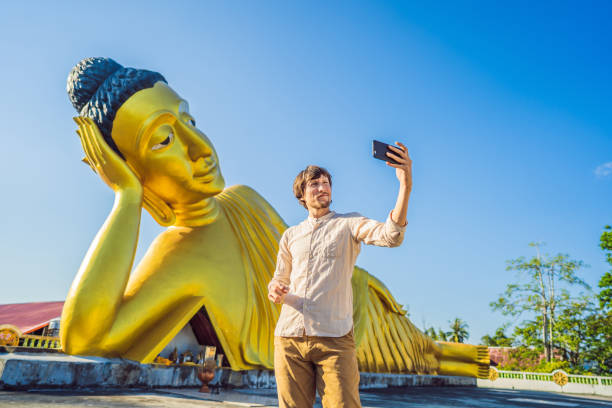 istock Happy man tourist on background ofLying Buddha statue 1156831449