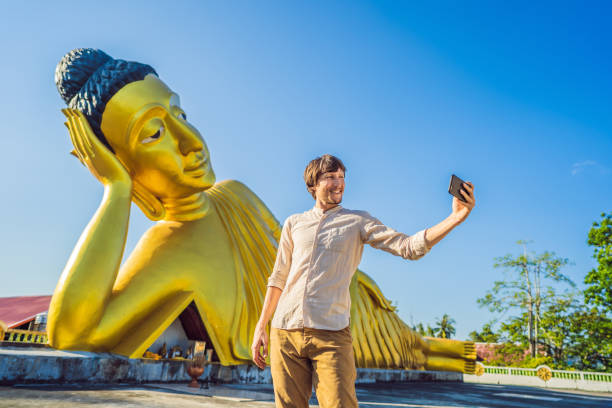 istock Happy man tourist on background ofLying Buddha statue 1156831586