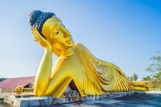 statua del buddha sdraiata fatta con sfondo cielo blu - reclining buddha foto e immagini stock