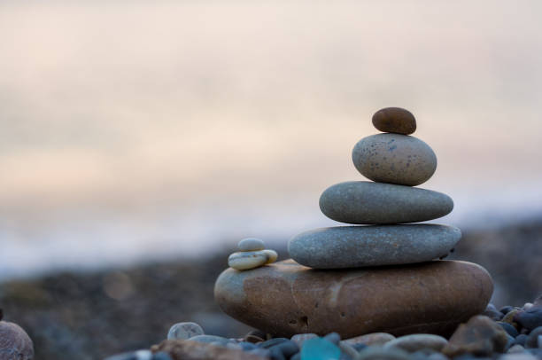 pila di pietre zen su pebble beach - cornerstone stability pyramid stone foto e immagini stock