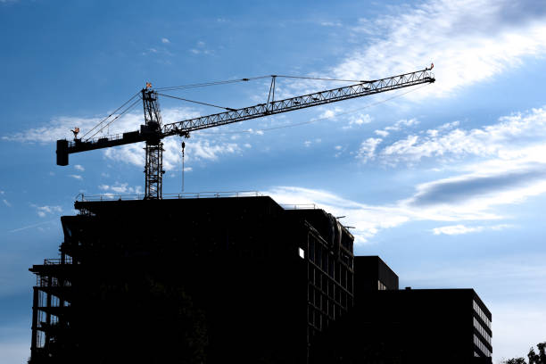 istock Construction crane on a top of a building. Afternoon silhouette 1156840094