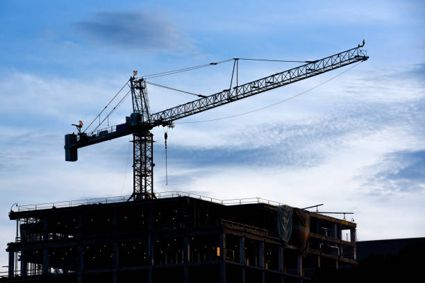 istock Construction crane on a top of a building. Afternoon silhouette 1156840097