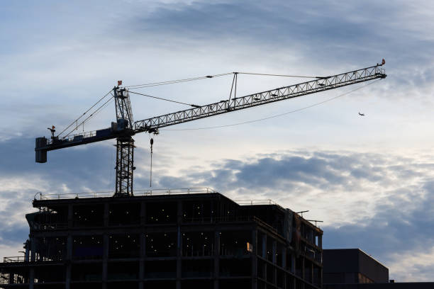 istock Construction crane on a top of a building. Afternoon silhouette 1156840628