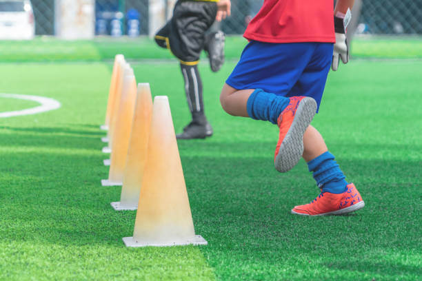 istock Children feet with soccer boots training on training cone on soccer ground 1156843481